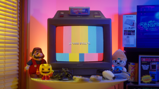 CRT TV with vertical color bars that says press start in pixelated font on a table with toys and a controler